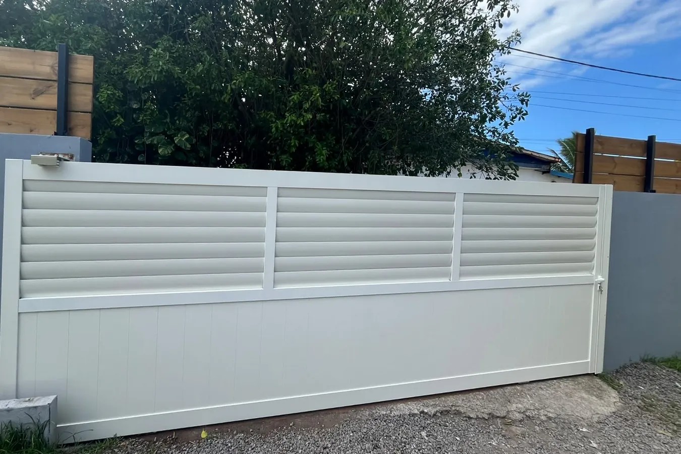 Le même portail remplacé par un portail coulissant aluminium blanc à persiennes, posé par Aluric OI