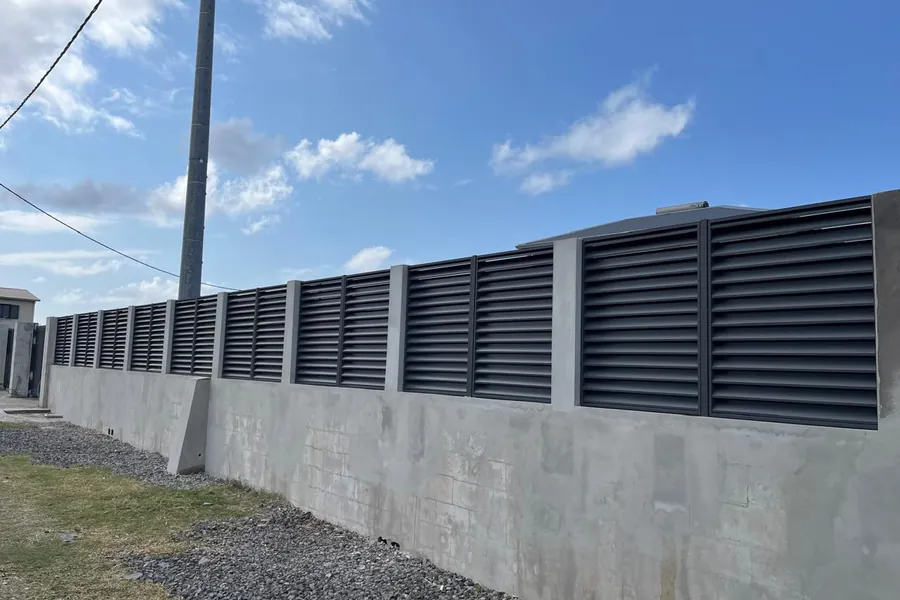 Clôture en panneaux brise-vue aluminium anthracite posés sur un mur béton