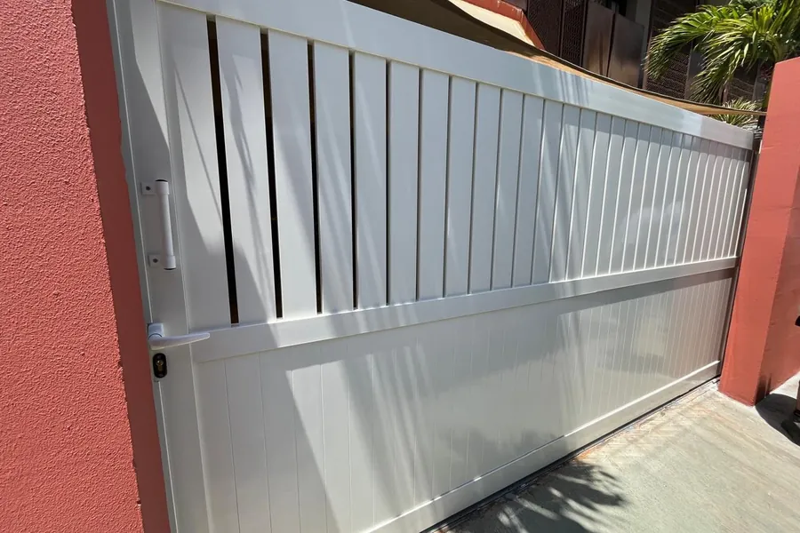 Portail coulissant aluminium blanc barreaudé en partie haute, bas plein à lames
