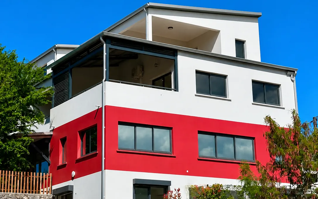 Fenêtres coulissantes aluminium anthracite sur une façade blanche et rouge
